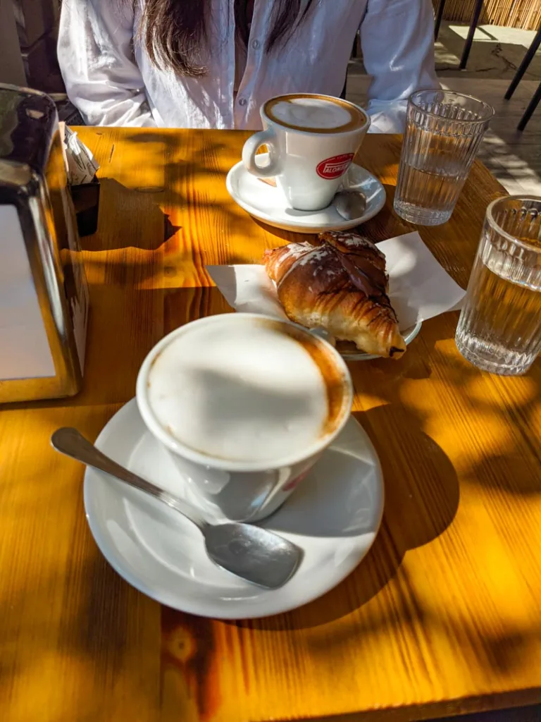 two cappuccinos and a croissant on the table at pezzoti gelateria in pigneto rome