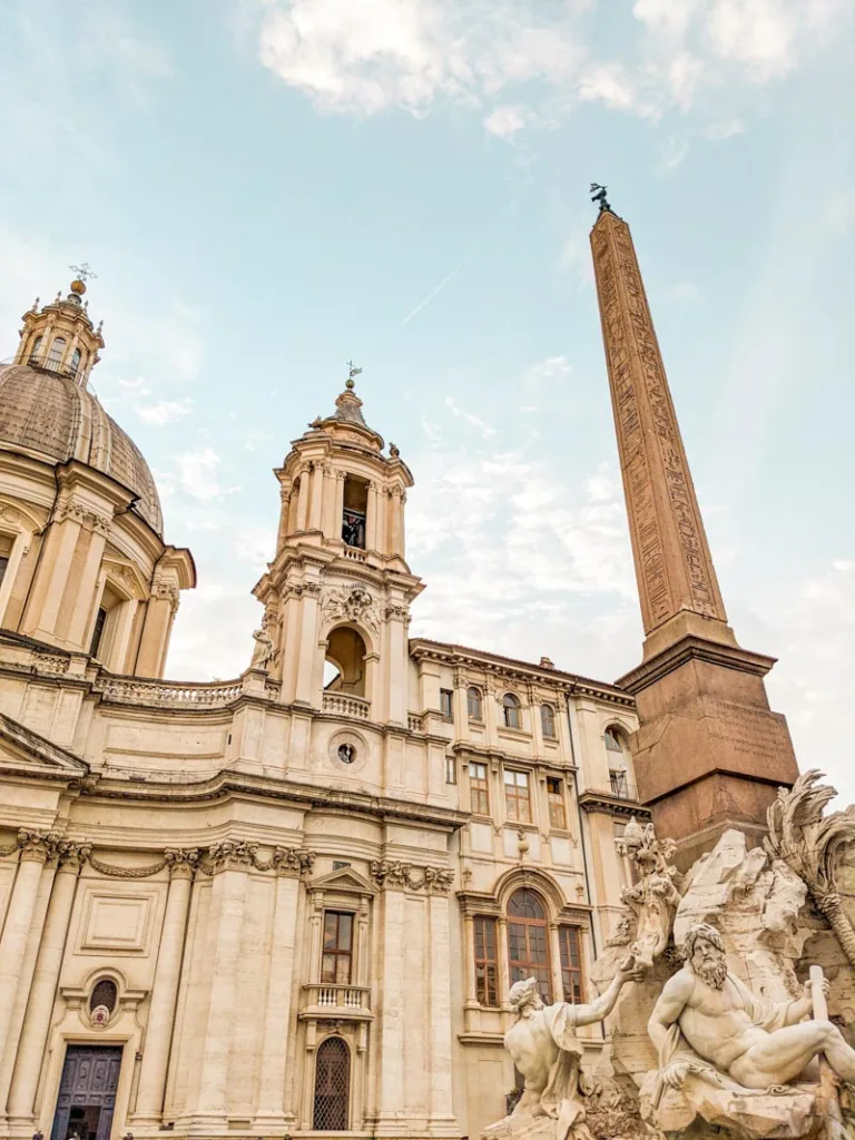 a view of a part of the fountain of the four rivers and the church of sant agnese in piazza navona, rome