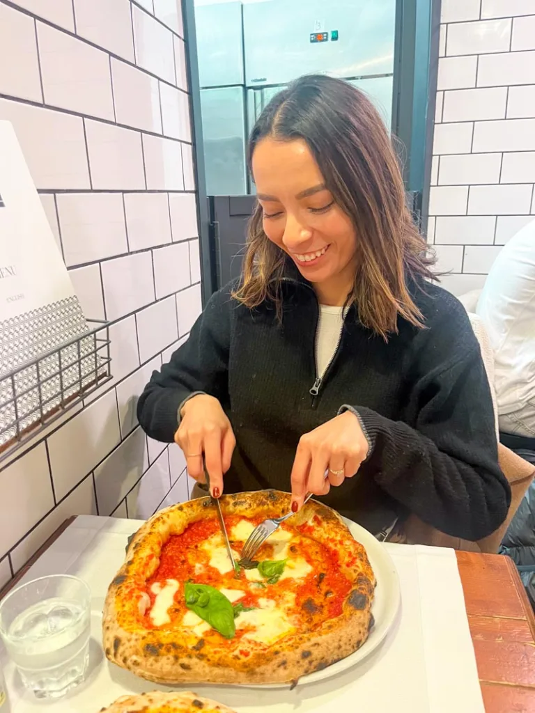 woman smiling cutting a margherita pizza at piccolo buco in rome