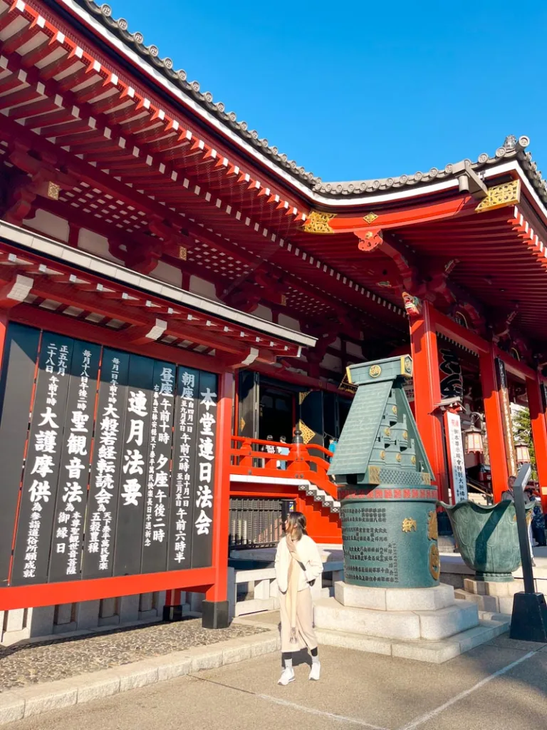 woman standing in front of the red wooden senso-ji temple in asakusa tokyo