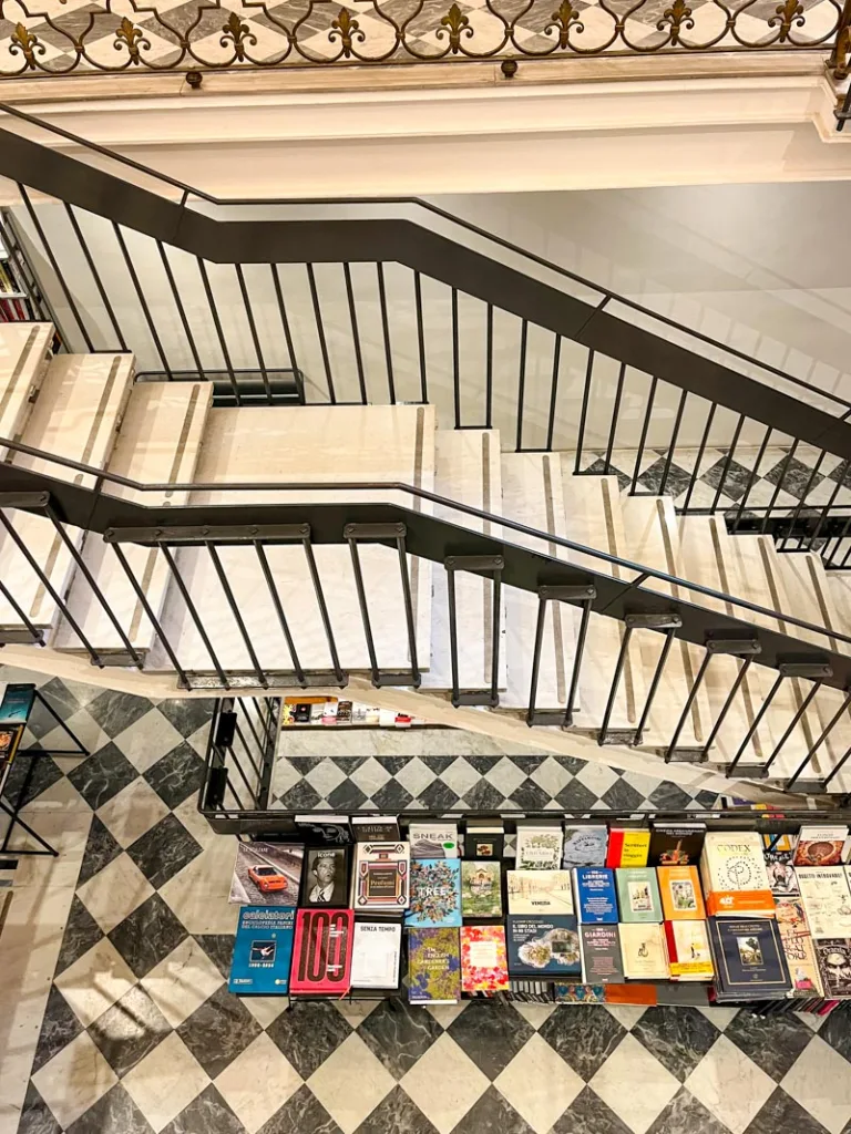 second floor view of the checkered tile floor and a table with stacks of books at Spazio Sette Libreria in rome