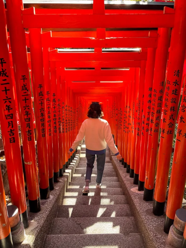 woman walking down the thousand torii gates tunnel in tokyo
