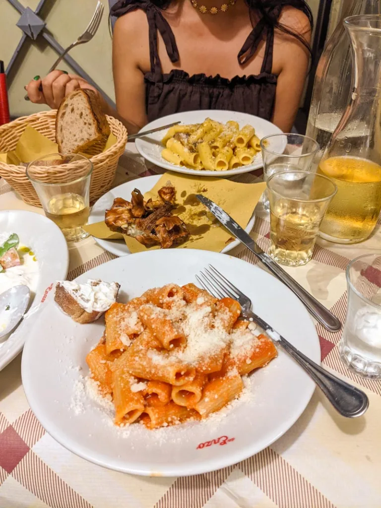 bowls of pasta, a plate of artichoke and a bread basket at trattoia da enzo al 29 in rome