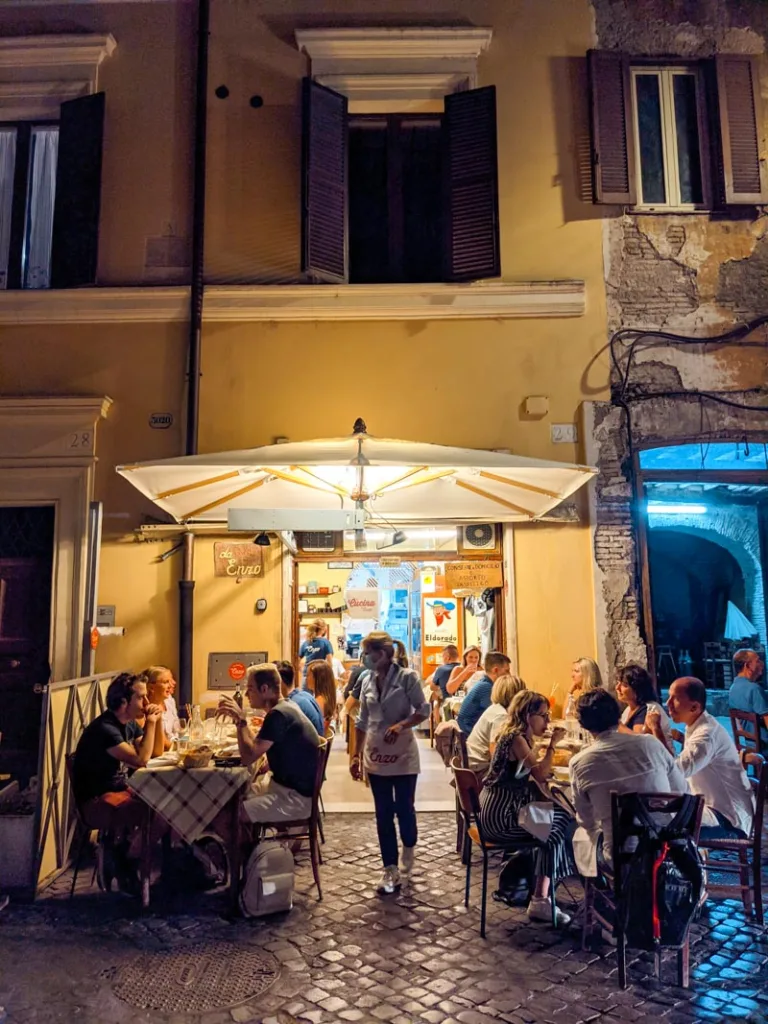 people dining outside in the evening at trattoria da enzo al 29 in rome