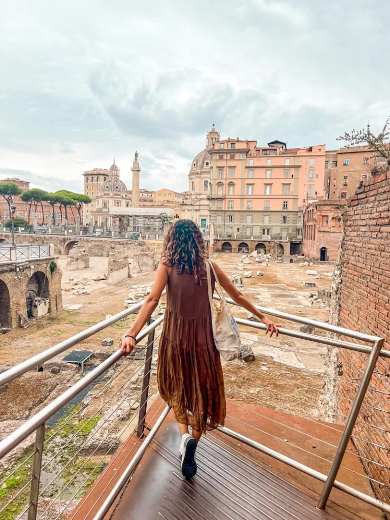 woman looking out at the roman forum from a tucked away entrance in via campo carleo in rome