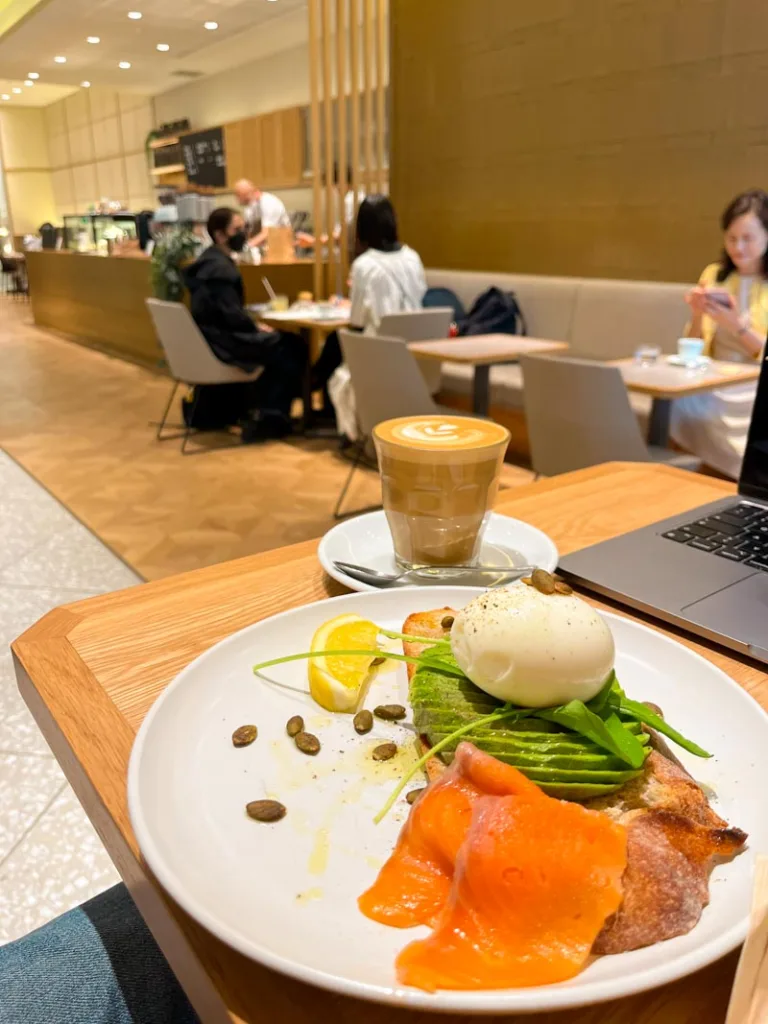 plate with an avocado toast with an egg on top and a side of smoked salmon and a cappuccino at allpress tonaromon in tokyo