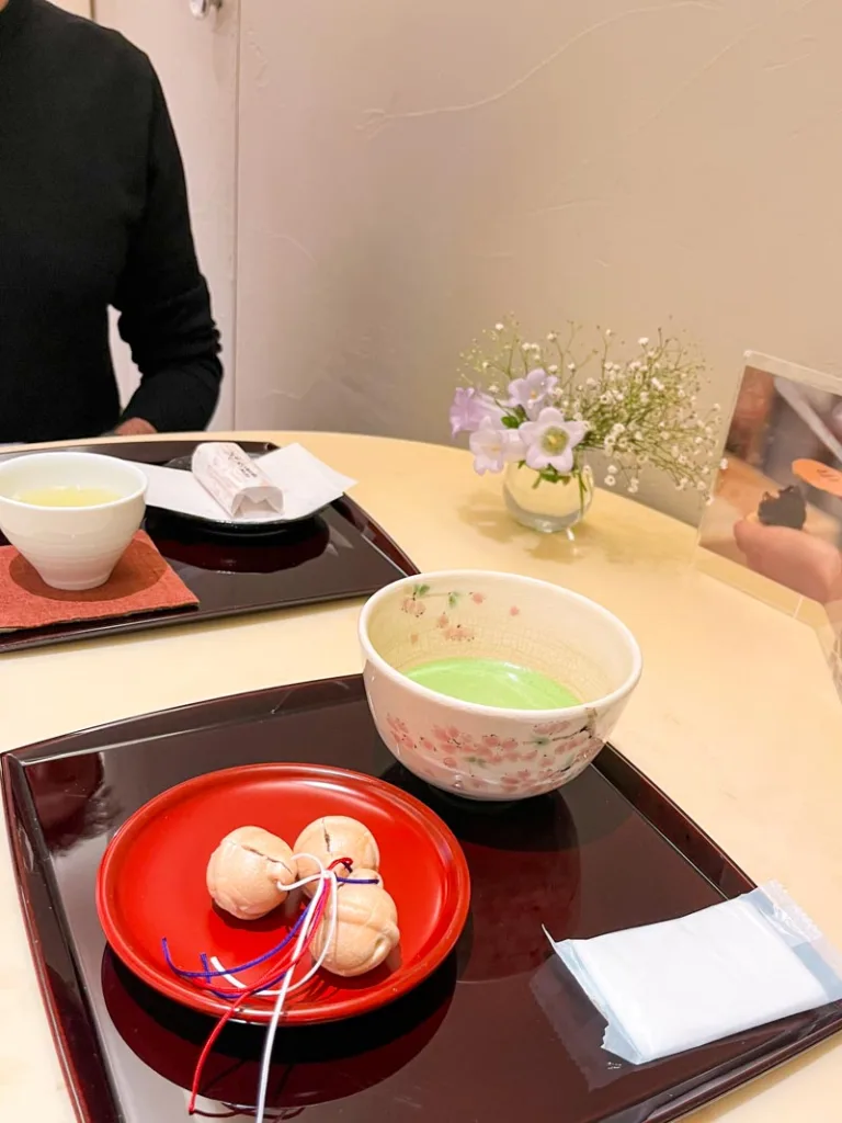 two trays on a table with a green tea bowl and small japanese sweets at a traditional confectionary shop in tokyo