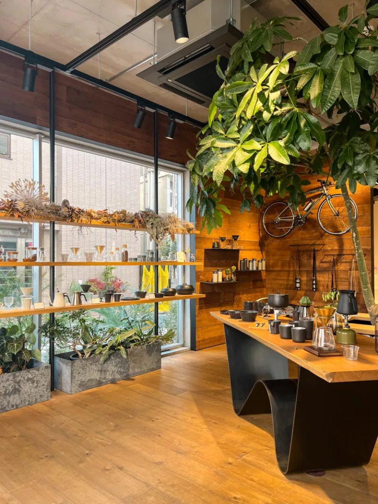 wooden floors, big glass walls, plants and minimalist display of items at a kinto store in tokyo