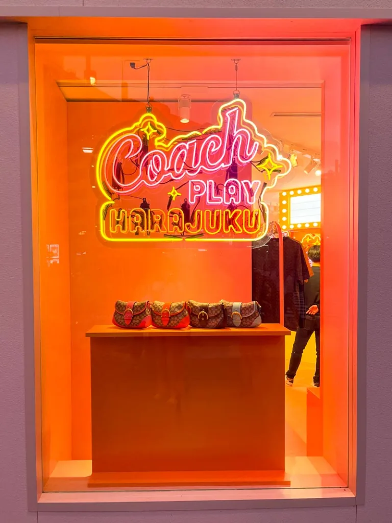 neon light display reading "coach + play harajuku" in tokyo