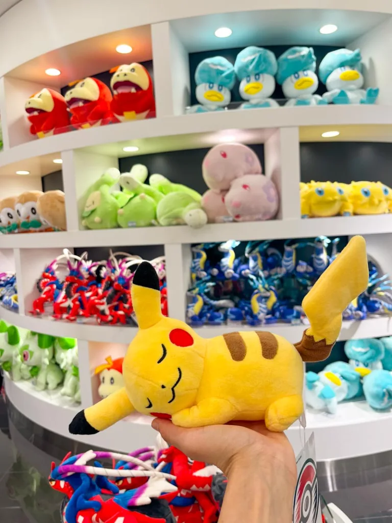 hand holding a small stuffed sleeping pikachu at pokemon center in tokyo