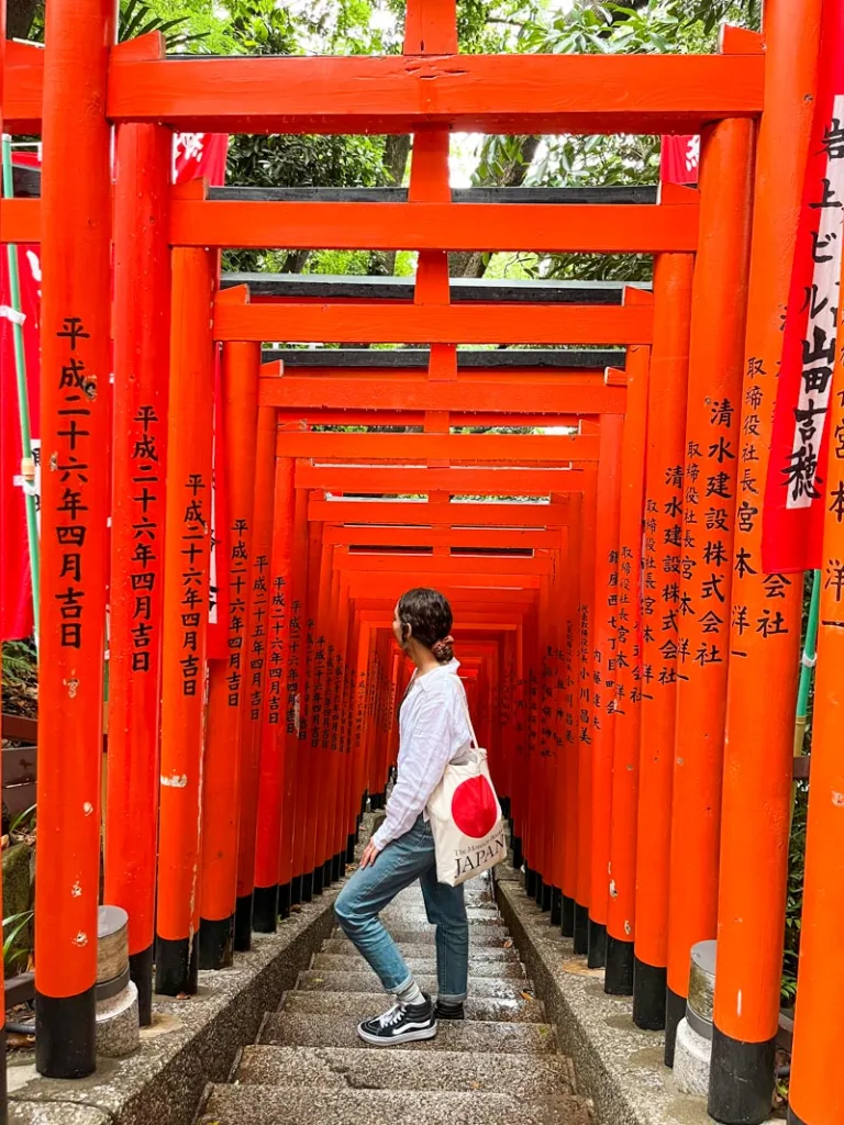 woman standing in the middle of a staircase lined by lots of torii gates at the thousand torii gates in tokyo