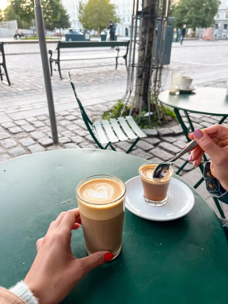 a latte and a cortado on an outdoor green metal table at coffee collective in copenhagen