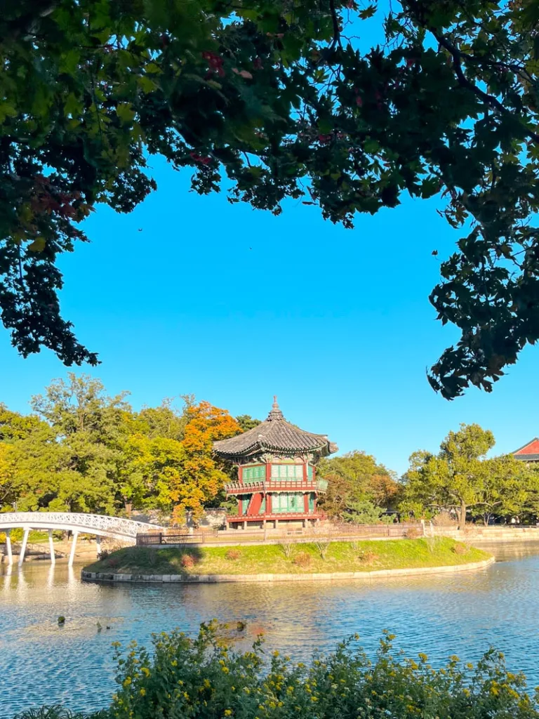 view of a lake and a small temple on a small island at gyeongbokgung palace in seoul in autumn