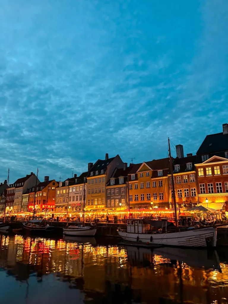 colorful houses of Nyhavn, copenhagen lit up at night by the restaurants along the street