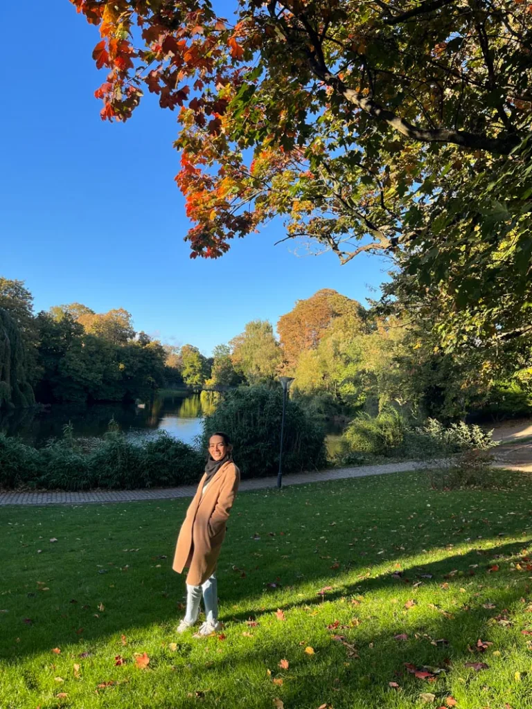 woman standing on the grass with a view of a lake behind at Orstedsparken in copenhagen