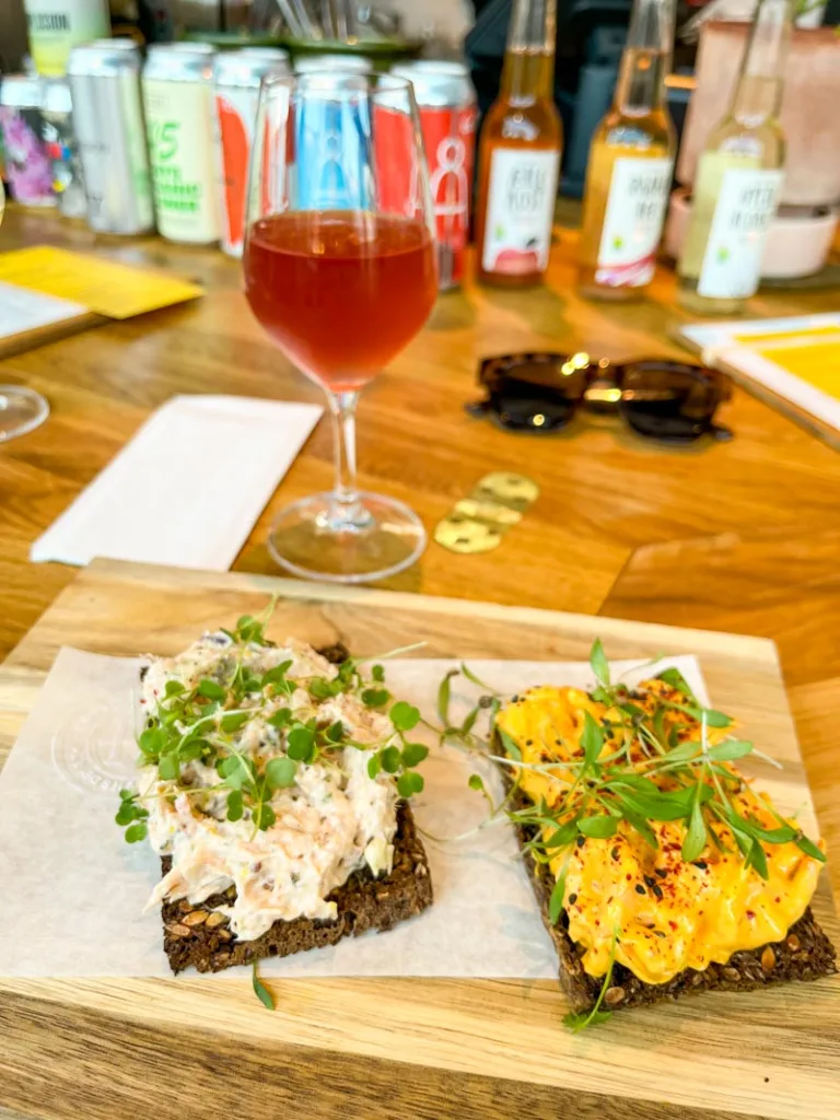 two smorrebrod on a wooden board and a glass of rose wine at rort restaurant in copenhagen