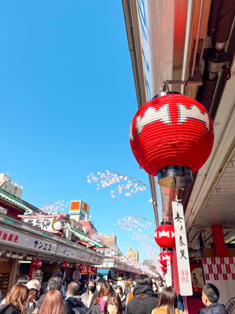 small red lanterns lining the way and crowds walking through nakamise shopping street in asakusa, tokyo
