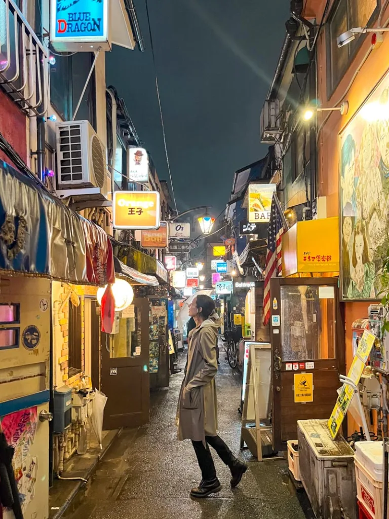 woman standing in the middle of the tight streets of golden gai in shinjuku, tokyo