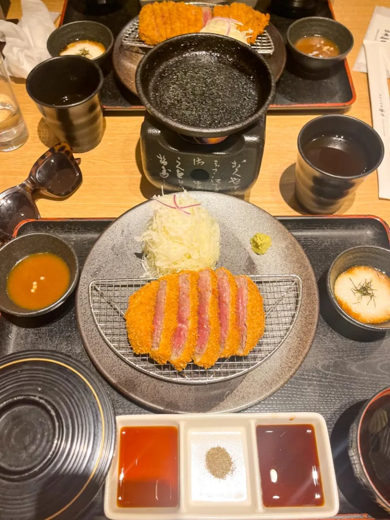 plate with breaded slice beef and many small side sauces at gyakatsu motomura in japan