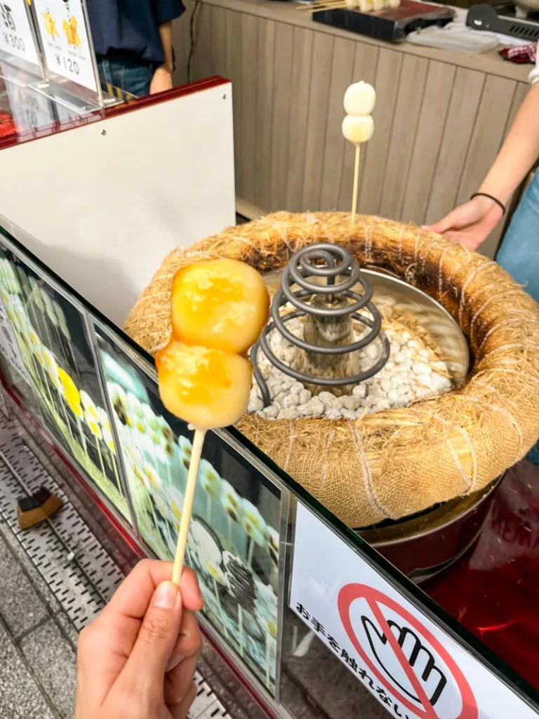 hand holding a stick of mitarashi dango from nakamise street in asakusa, tokyo