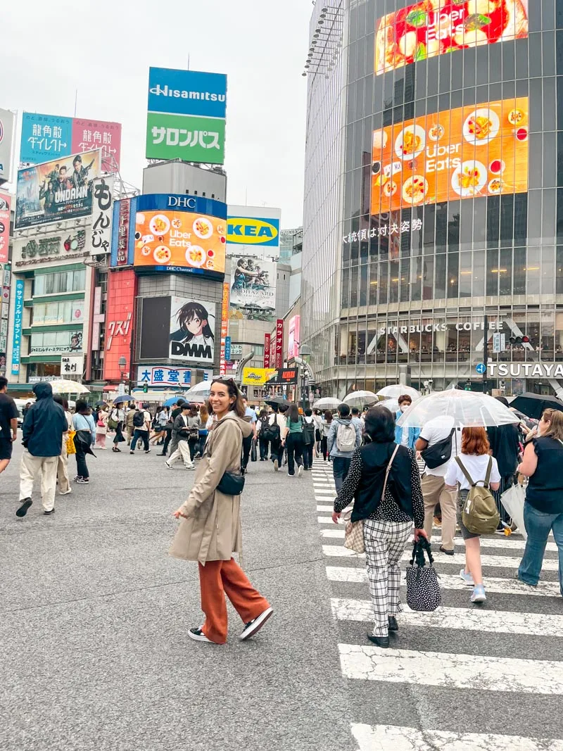 woman standing in the middle of the busy shibuya crossing in tokyo