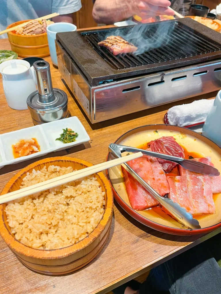 plate with tuna steaks, a rice bowl, small side seasoning bowls and a table grill at a restaurant in tsukiji fish market in tokyo