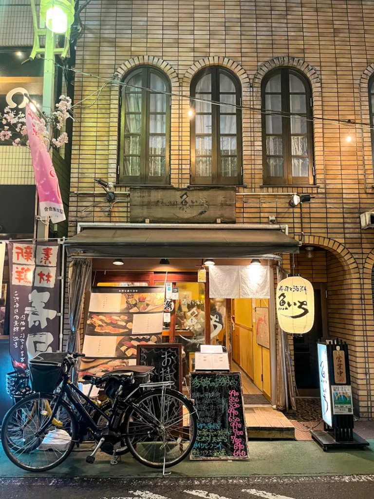 small facade of uoichi sushi restaurant in nakameguro tokyo with menu pictures outside