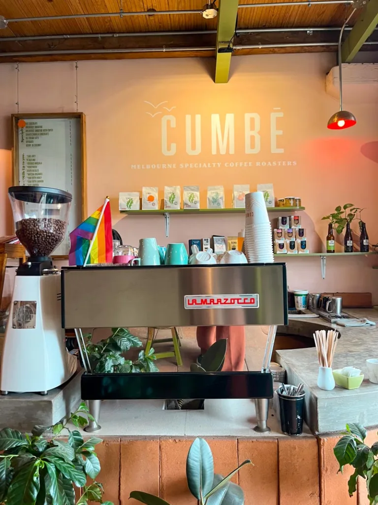 pink walls and a cumbe logo painted in white letters above the coffee machine in a coffee shop in mexico city