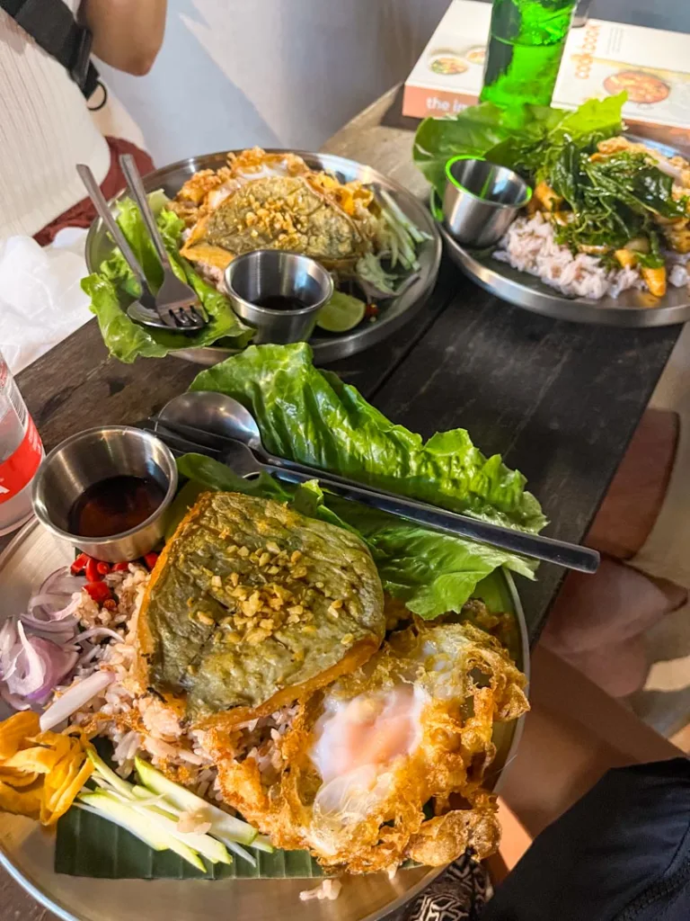 three plates with fried fish and vegetables at cattago restaurant in koh tao, thailand