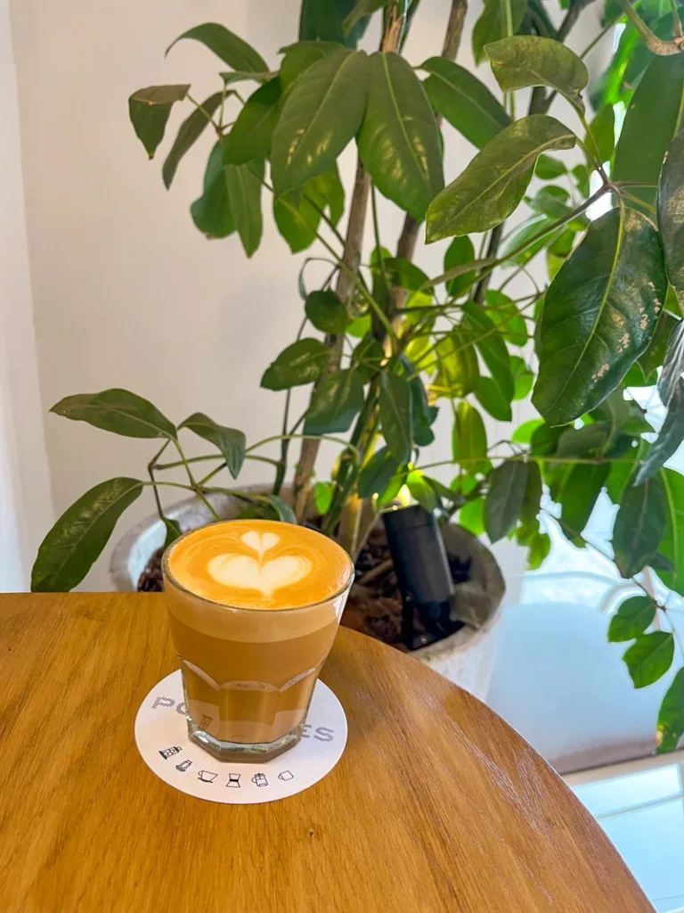 a flat white on a glass on a wooden table at postales coffee shop in mexico city