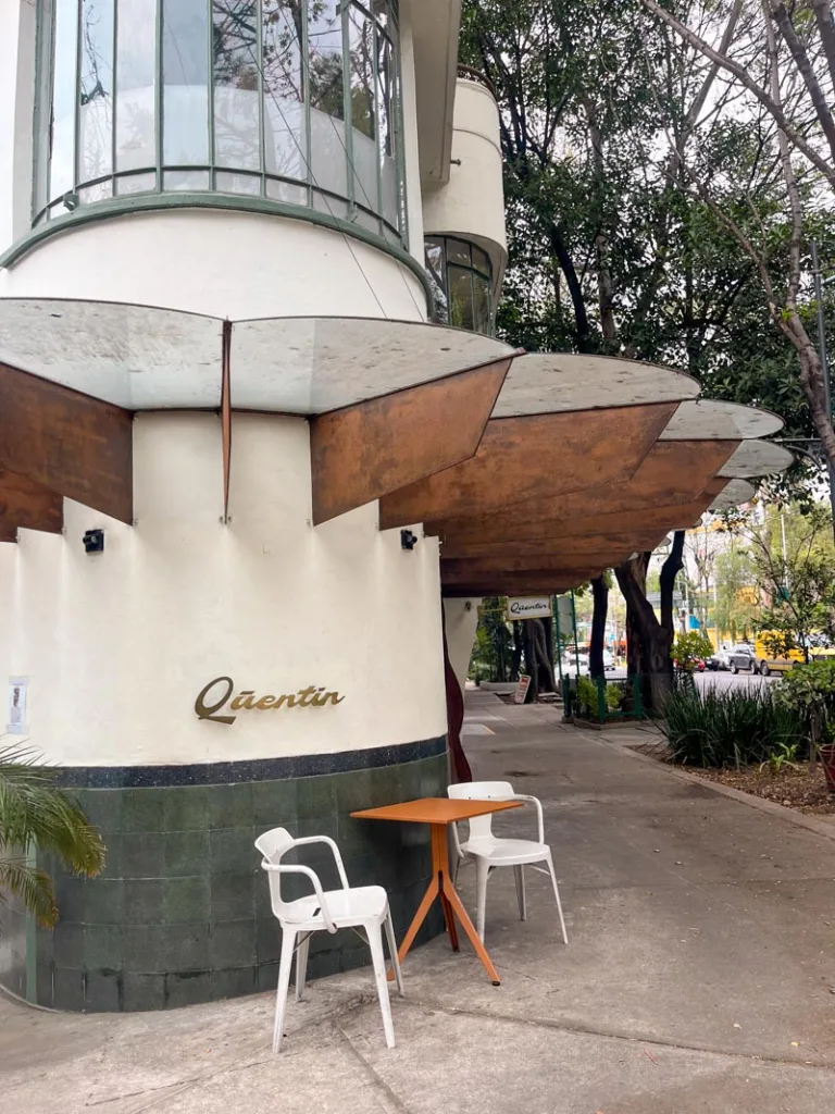 two chairs and a table next to the quentin logo at the coffee shop in roma, mexico city