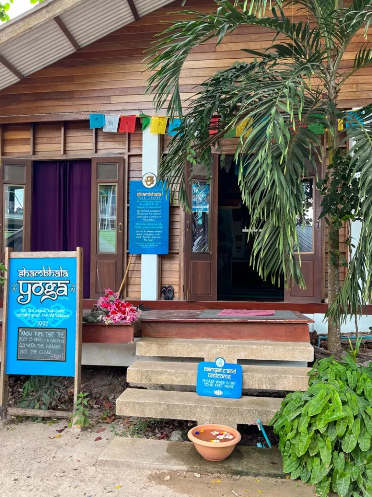 wooden facade of shambhala yoga studio with colorful flags hanging over the door in koh tao, thailand