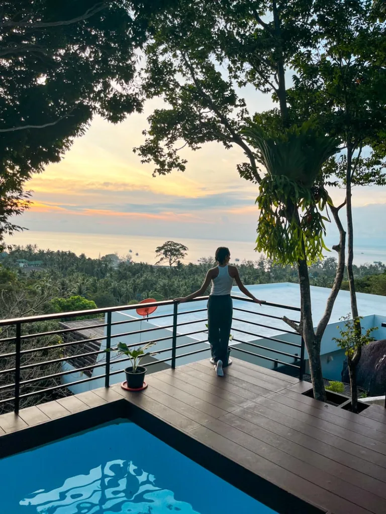 woman standing on a balcony with a pool looking out at the ocean in matina mountain resort, koh tao