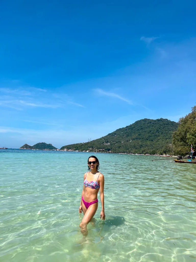 woman in a bikini standing in the crystal clear ocean in koh tao, thailand