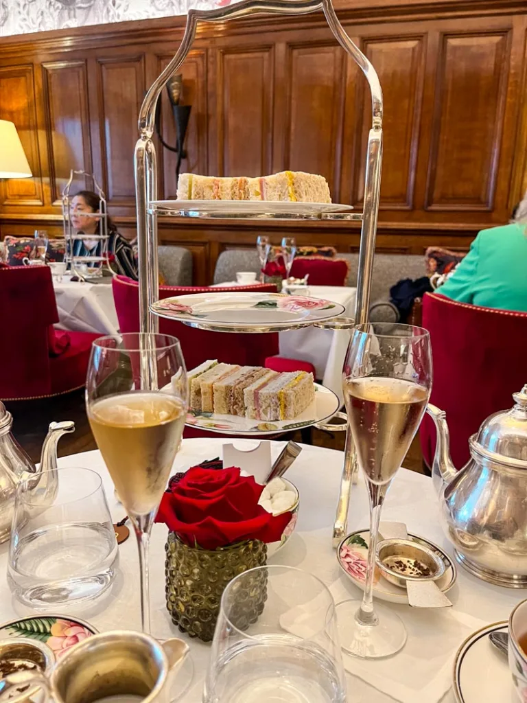 two prosecco glasses and a cake stand with finger sandwiches at afternoon tea in browns hotel, london