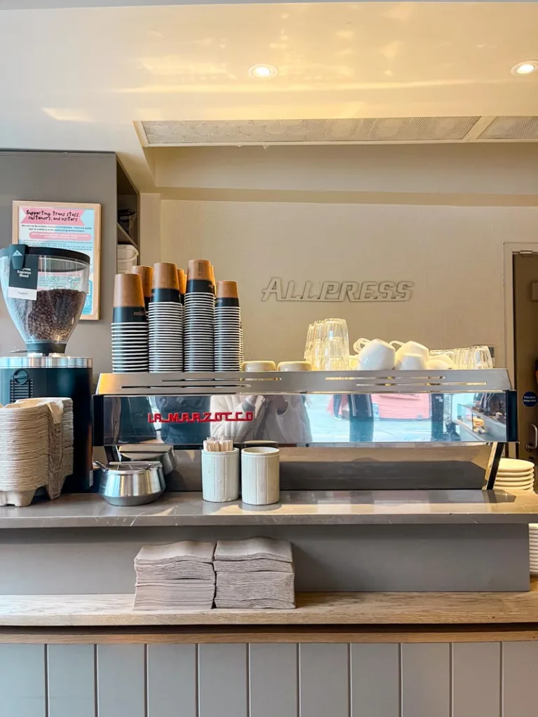 light grey interior, espresso machine with cups on top of it at allpress espresso coffee shop in shoreditch, london
