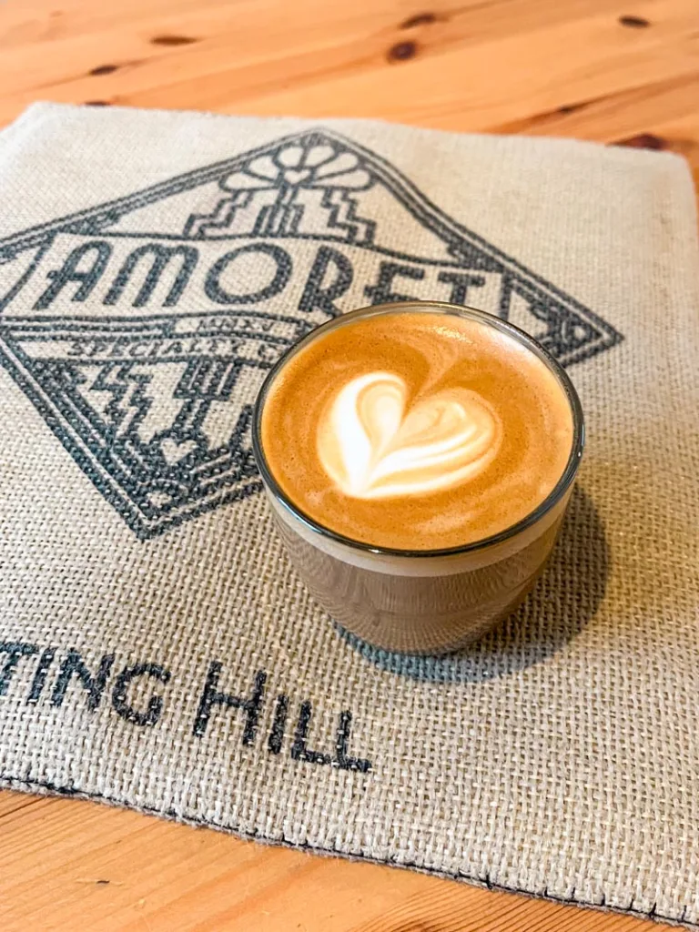 flat white on a branded amoret coffee cotton bag on a table at amoret coffee shop in london