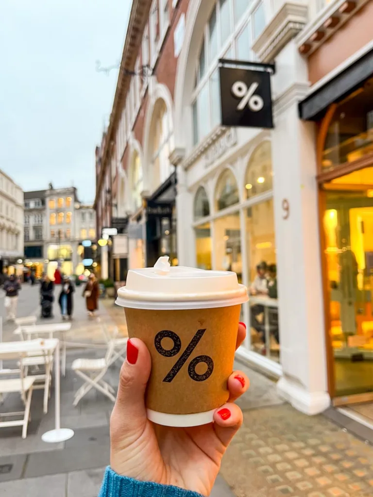 hand holding a takeaway %arabica coffee cup in covent garden, london