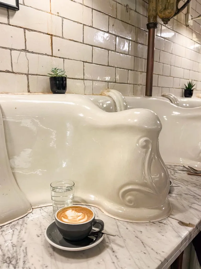 Latte served inside the unique tiled interior of Attendant Coffee Roasters in London