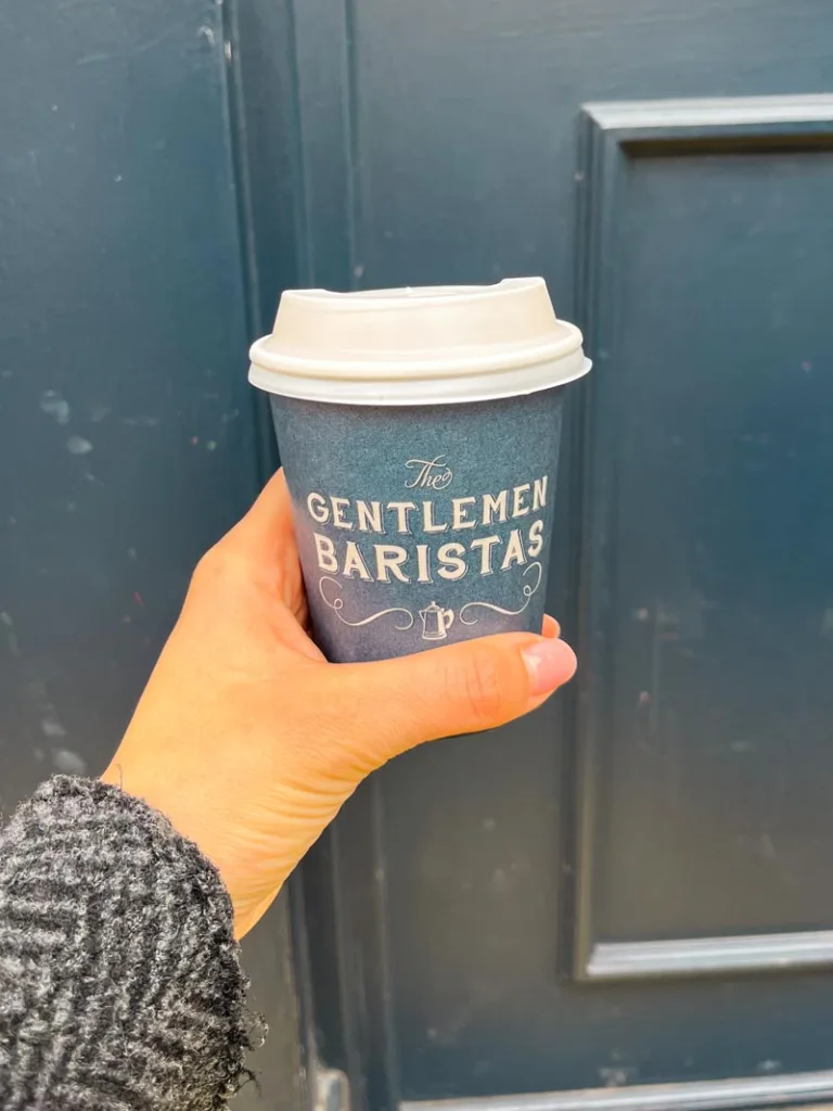 hand holding a takeaway coffee cup from gentlemen baristas in borough market, london