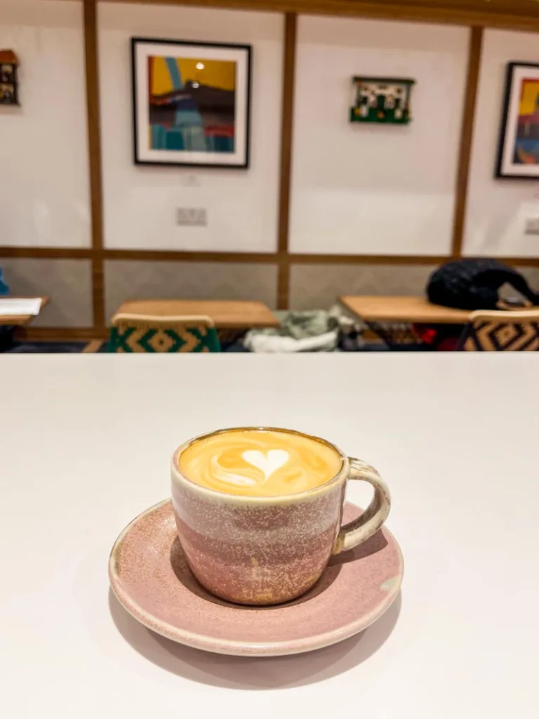 latte on a baby pink cup and plate at hermanos colombian coffee shop in notting hill, london