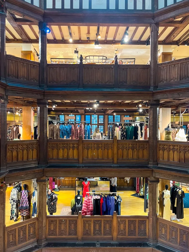 old, wood balconies, inside of libertys london and racks of clothes on the floors