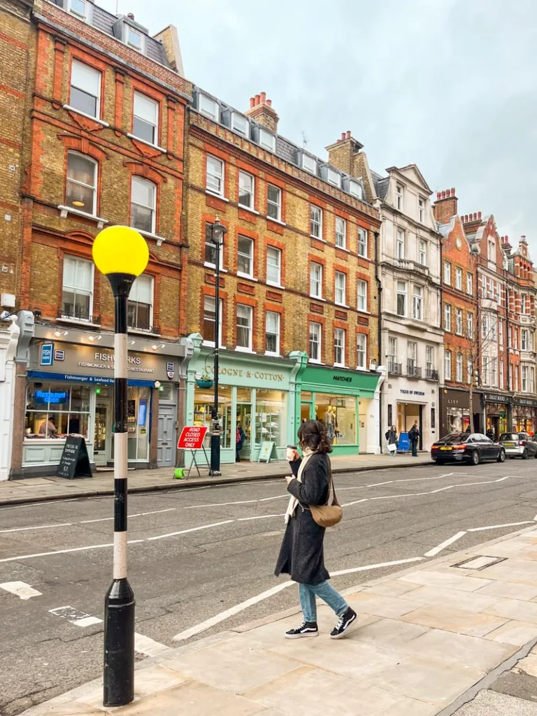 woman standing on a sidewalk in front red brick houses in marylebone, london
