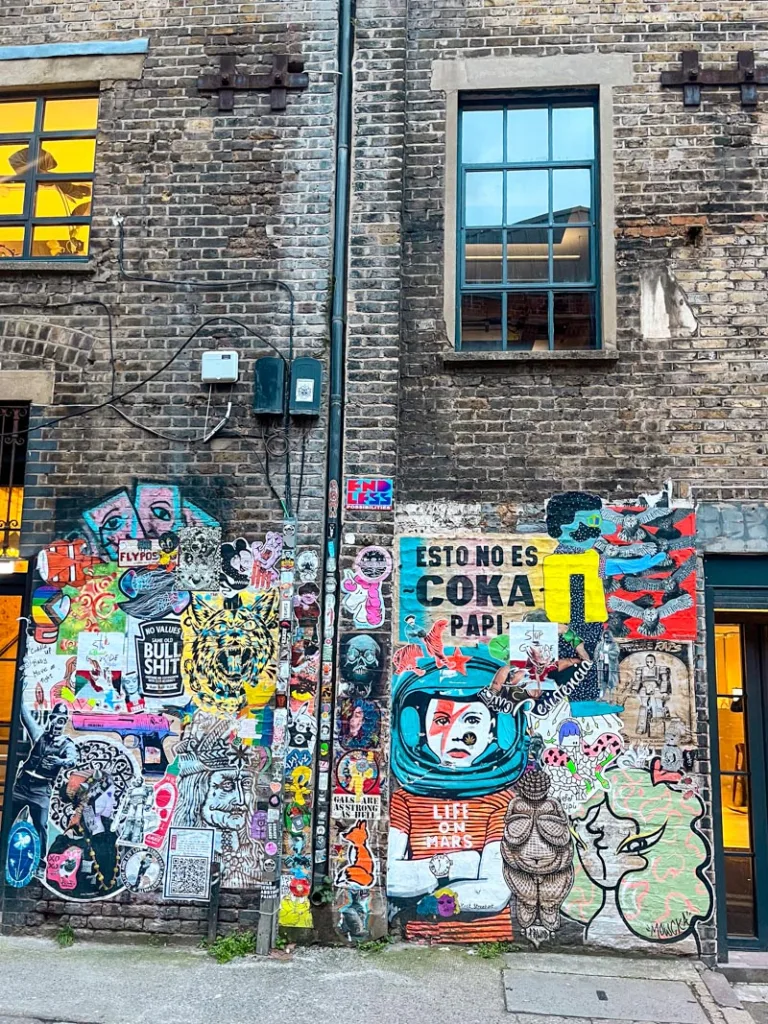 a brick ball with lots of grafitti and stickers on it in shoreditch, london
