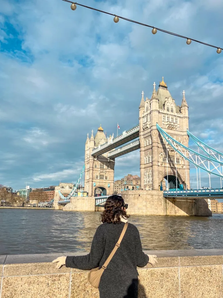 woman standing on the south side of the river thames looking out at the tower bridge in london
