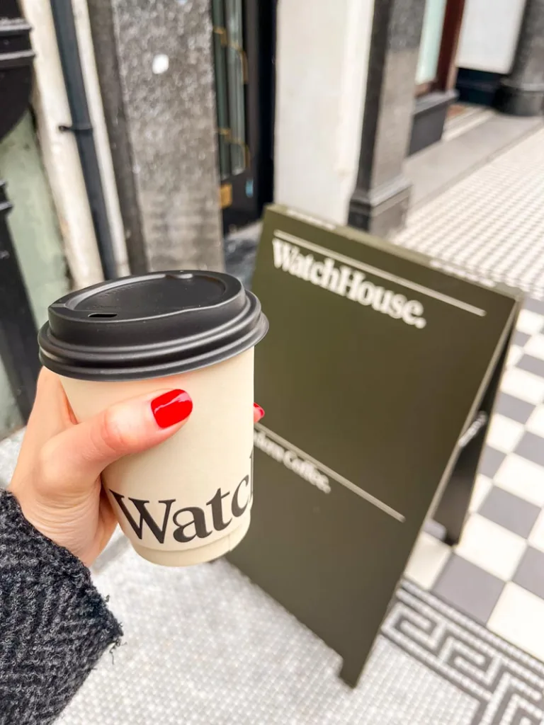 hand holding a takeaway coffee cup from watch house coffee shop in covent garden, london