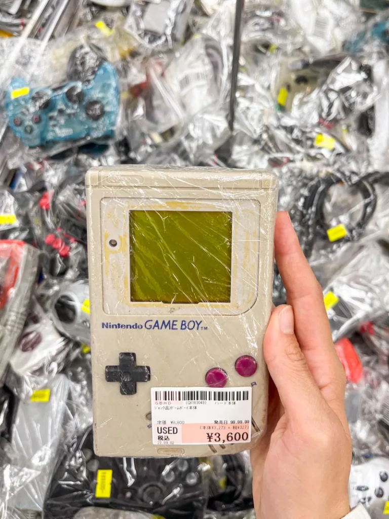 hand holding a retro game boy at a shop in nipponbashi denden town in osaka