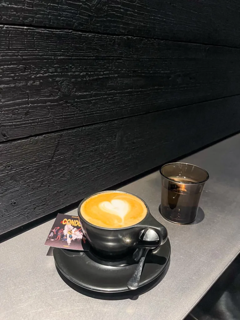 cafe con leche served in a black mug, on a silver bar at hidden coffee roasters in barcelona