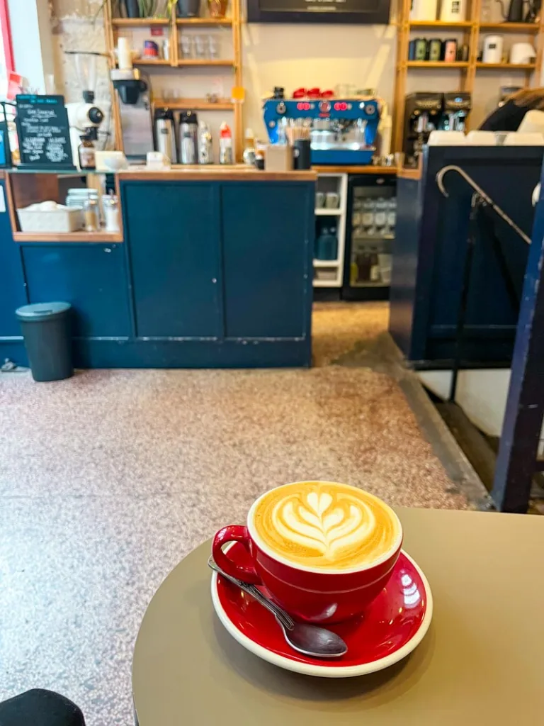 capuccino on a red ceramic mug at beans on fire coffee shop in paris with a view of the blue coffee bar behind