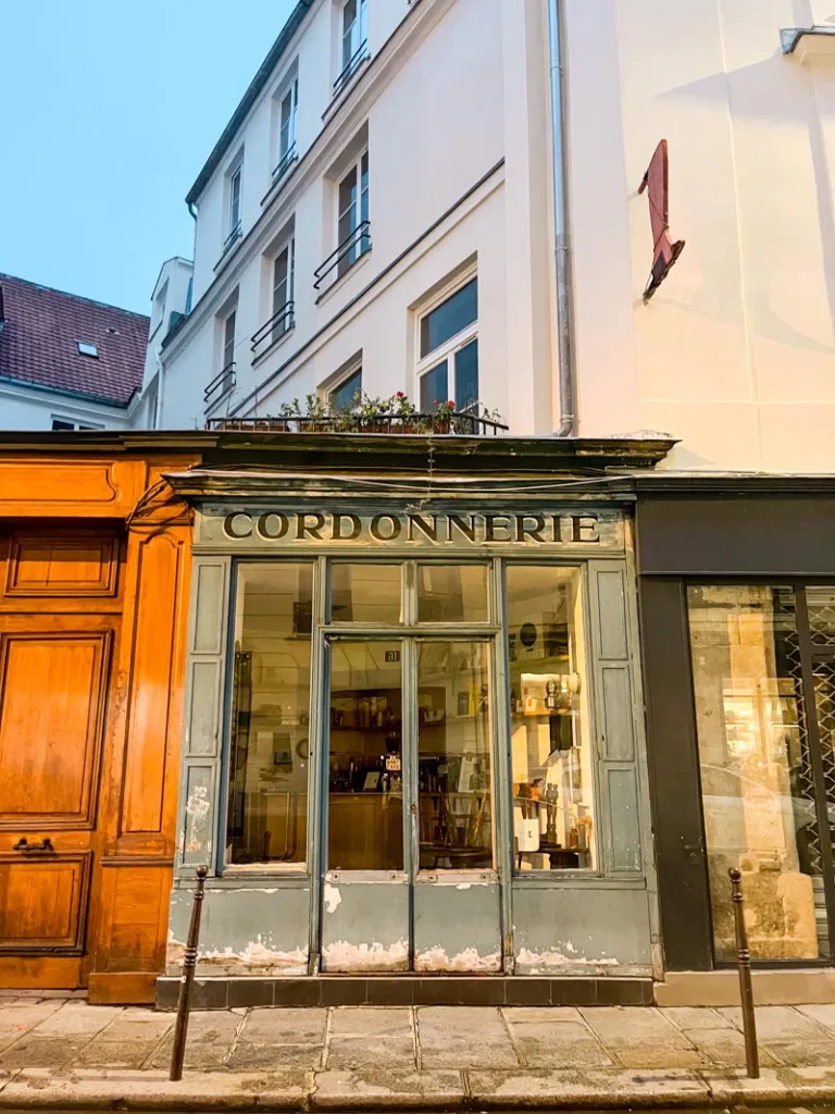 charming old-school blue-wood facade with cordonnerie written at the top housing boot cafe in paris